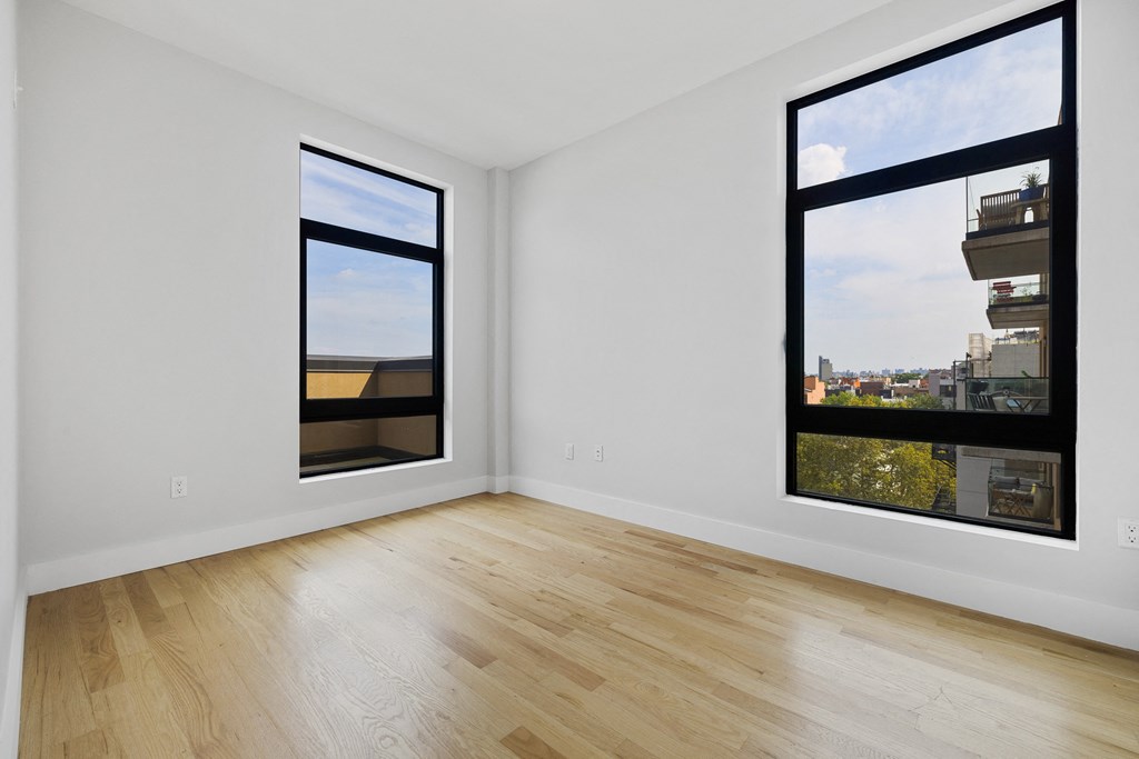an empty living room with large windows and a wooden floor